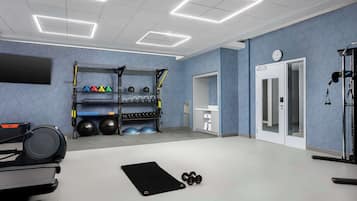 Une salle de sport équipée de matériel d’exercice, d’un tapis noir, d’haltères et d’un support mural pour les poids.