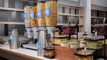 Uma mesa de buffet com diversos recipientes de comida e uma estação de café.