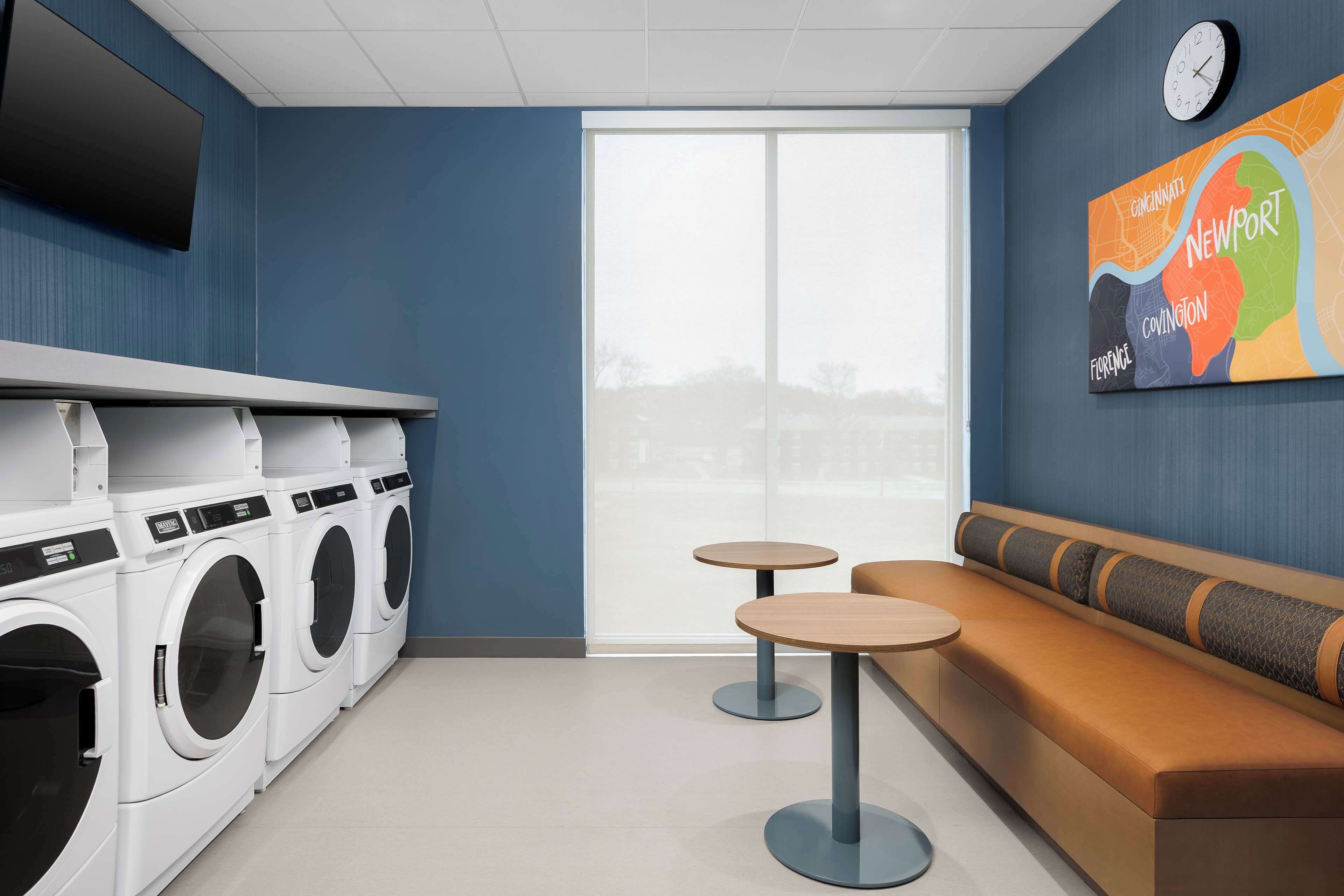 A laundry room with a large window, a wall-mounted clock, and a colorful map.