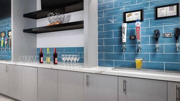 Una zona de bar con azulejos azules, una barra con vasos y botellas, y una grifo de cerveza Coors.