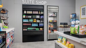 A suite shop with shelves stocked with beverages, snacks, and packaged goods. - Homewood Suites By Hilton Newport Cincinnati (Newport)