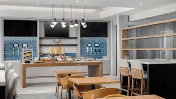 Una cocina moderna con una isla central, electrodomésticos integrados y una zona de estar con mesas y sillas de madera.