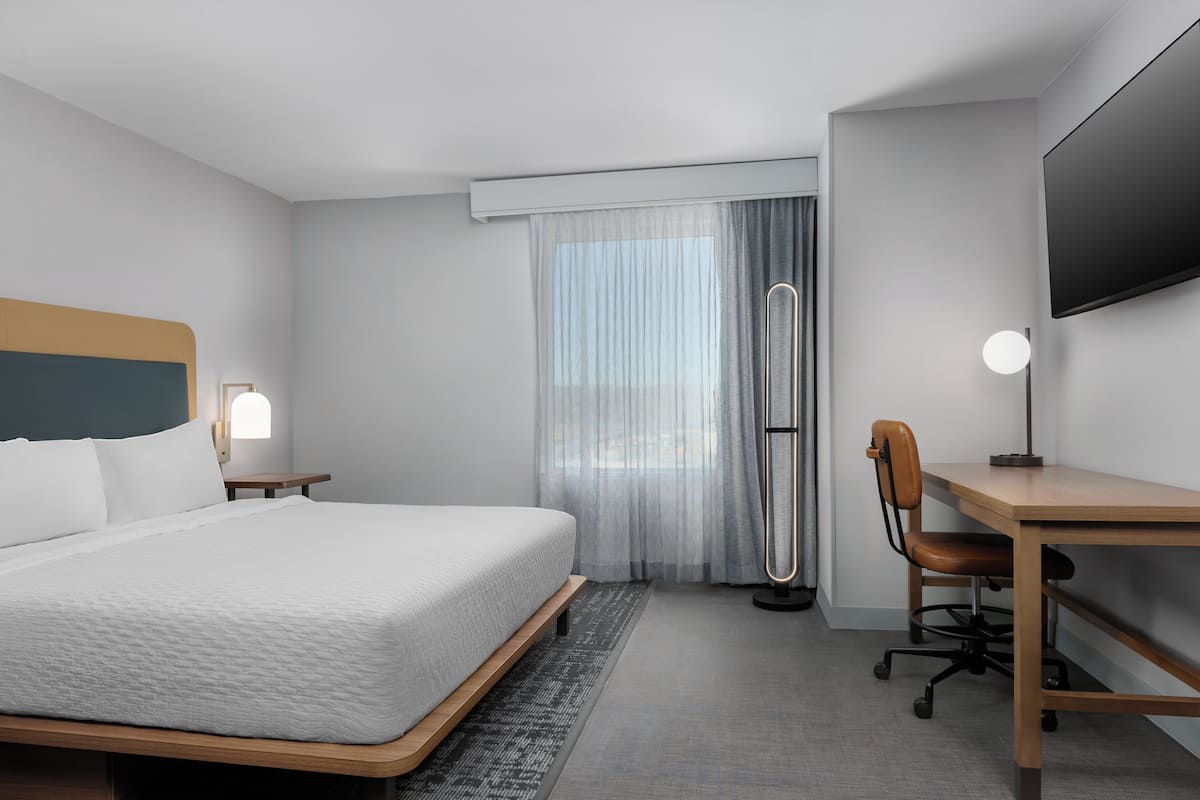 Una habitación de hotel moderna con una cama grande, un escritorio y un televisor.