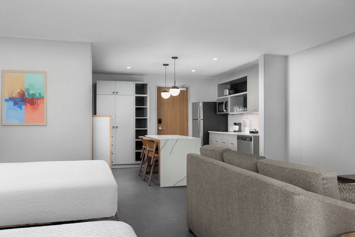 Un espacio habitable moderno y funcional con kitchenette, comedor y sofá.