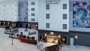 A modern hotel building with "Homewood Suites by Hilton" signage, outdoor seating area, and a large mural on the side. - Homewood Suites By Hilton Newport Cincinnati (Newport)