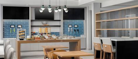Een moderne keuken met een centraal eiland, een bar en een grote televisie.