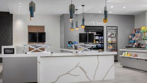 A modern hotel reception area with a marble counter, a flat-screen TV, and a minibar. - Homewood Suites By Hilton Newport Cincinnati (Newport)