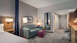 Une chambre d’hôtel avec un lit, un canapé, un bureau et un miroir.