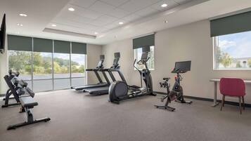 Une salle de sport équipée de tapis de course, de vélos elliptiques et de bancs de musculation.