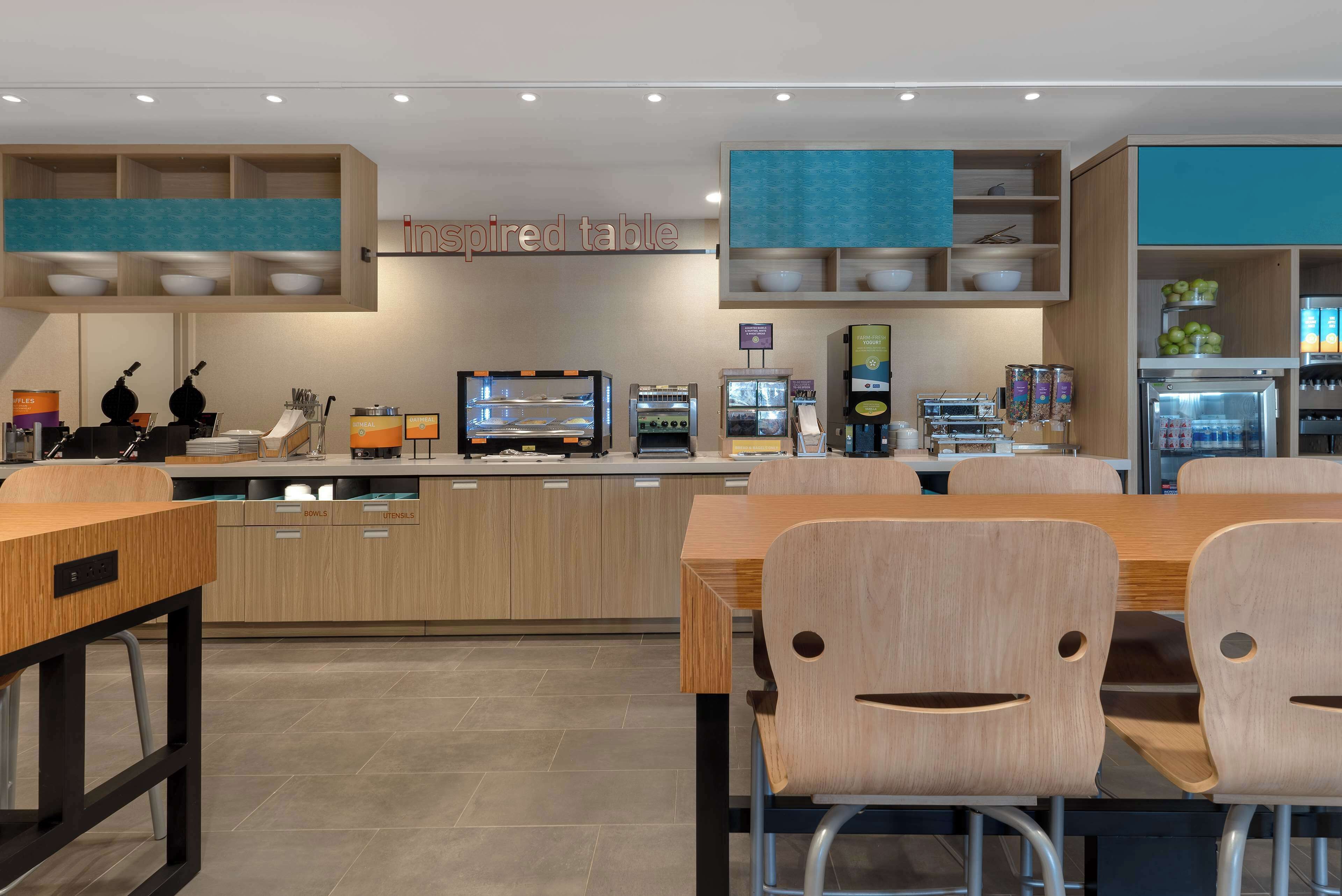 A modern restaurant with a central island, seating area, and various food service stations.