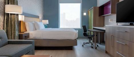 Una habitación de hotel moderna con una cama, un escritorio, un televisor y una zona de estar.