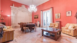 A dining area with a chandelier, a table set for four, and a sofa.