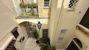 A narrow courtyard with a wrought iron gate, potted plants, and a lantern.