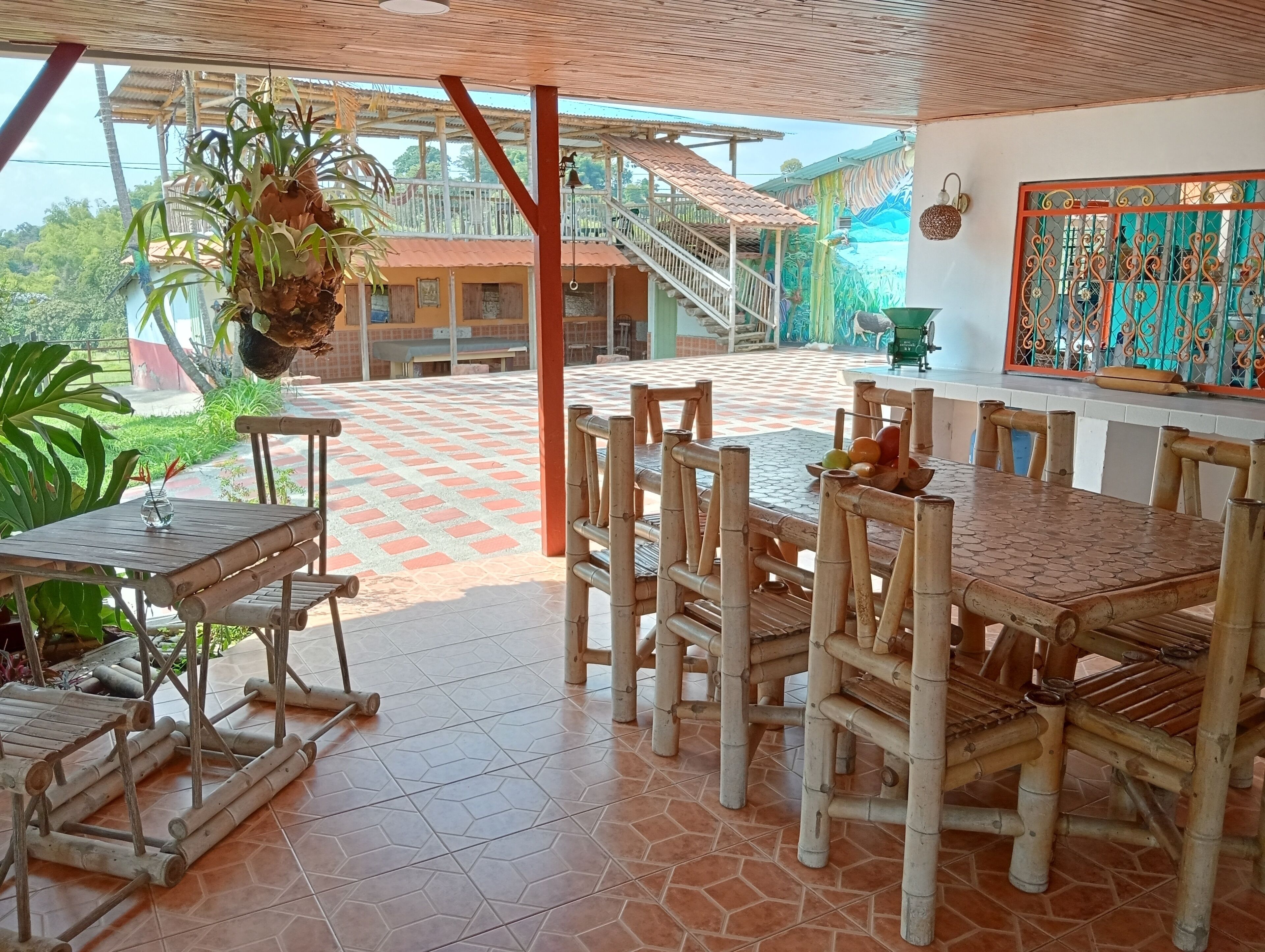 A covered outdoor dining area with bamboo furniture and a tiled floor.