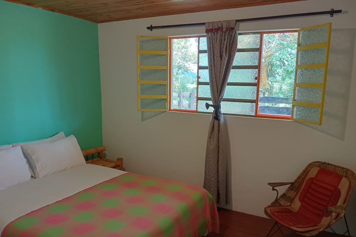 Une chambre à coucher avec un lit, une chaise et une fenêtre avec des rideaux.