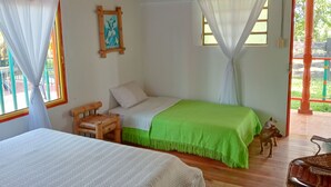 A room with a bed, a chair, a small table, and a window with curtains. - Rancho Ventura (Filandia)