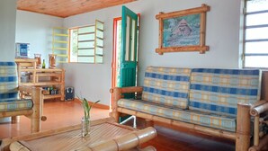 A room with a wooden ceiling, a sofa with a plaid cushion, a bamboo coffee table, a small plant, and a painting on the wall. - Rancho Ventura (Filandia)
