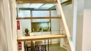 Un interior con varios niveles, que incluye una escalera, una zona de cocina y un comedor.