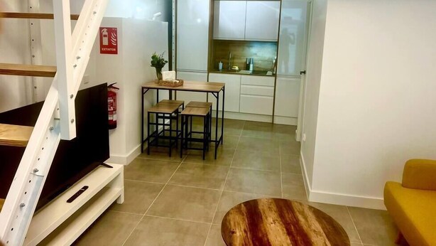 Un espacio habitable compacto con televisión, un pequeño comedor y cocina.