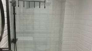 Un baño moderno con cabina de ducha de vidrio, un lavamanos blanco y encimera de madera.