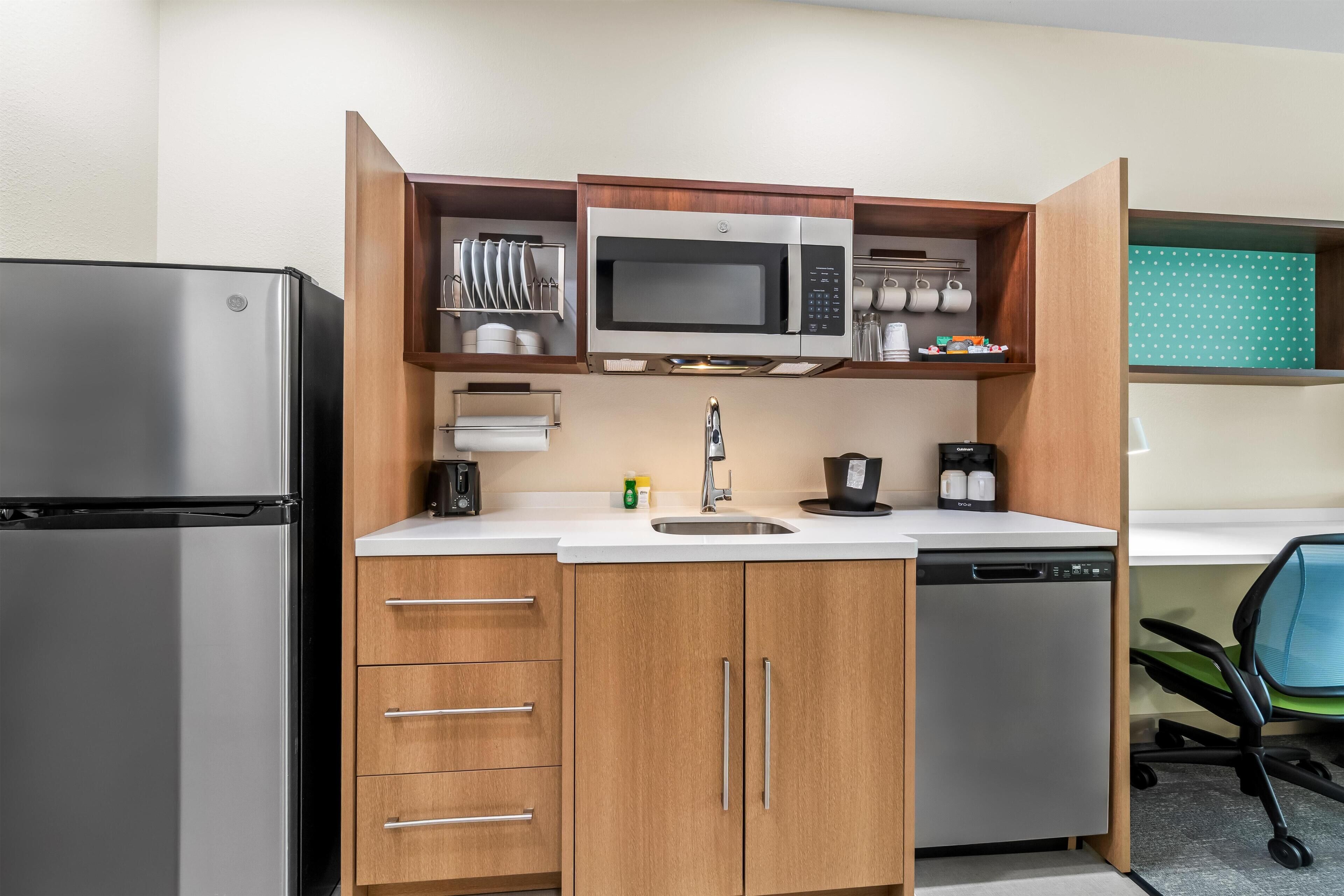 A compact kitchen with a built-in microwave, a coffee maker, and a dishwasher.