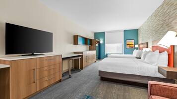 A hotel room with a bed, a desk with a flat-screen TV, a wardrobe, and a bathroom with a shower.