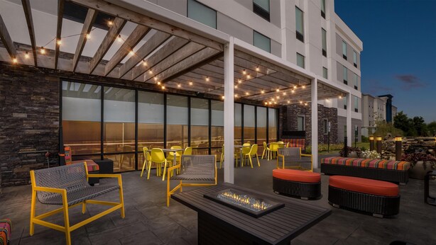 Un patio al aire libre con mobiliario, una chimenea y una zona cubierta con guirnaldas de luces.