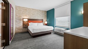 Una habitación de hotel con cama, mesita de noche, lámpara y ventana.