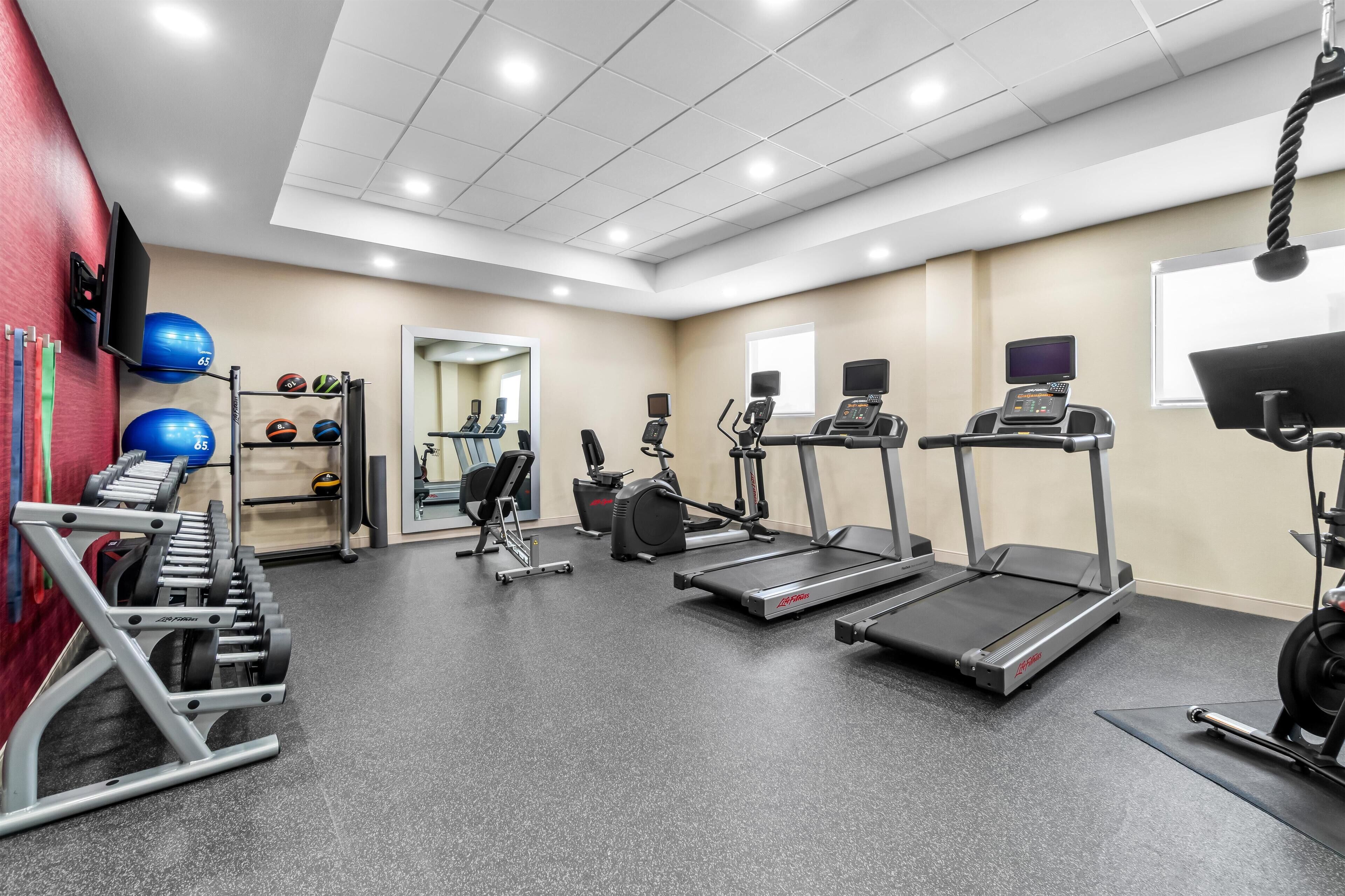 Un gimnasio con cintas de correr, elípticas y equipo de levantamiento de pesas.