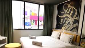 Una habitación de hotel con una cama, un ventanal con cortinas, un reposapiés amarillo y una pared con diseño negro y dorado.