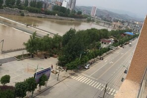 A river with a bridge, a road with vehicles, and buildings in the background.