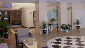 Eine Lobby mit Schachbrettmuster-Bodenbelag, Sitzgelegenheiten und Topfpflanzen.