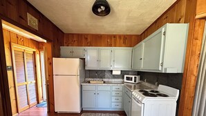 A compact kitchen with wooden walls, a refrigerator, a microwave, a stove, and light blue cabinets. - Rocky Racoon's Rustic Retreat at Sage Lake!  Dock slip & tons of fun await!! (Hale)
