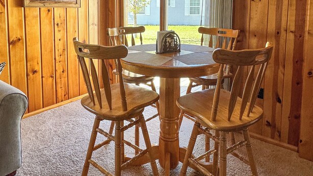 A wooden-paneled room with a round table and four chairs, a ceiling fan, and a window with a view of a house. - Rocky Racoon's Rustic Retreat at Sage Lake!  Dock slip & tons of fun await!! (Hale)