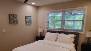 A bedroom with a bed, two nightstands, a window with blinds, and two wall art pieces. - Cozy 3 BR in center of town w/work space. Walking distance to main attractions  (Peachtree City)
