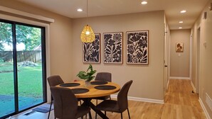 A dining area with a round table, four chairs, a hanging light fixture, and three framed floral artworks on the wall. - Cozy 3 BR in center of town w/work space. Walking distance to main attractions  (Peachtree City)