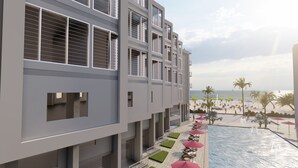 Ein modernes Hotel mit Poolbereich, Sitzgelegenheiten im Freien und Blick auf den Strand.