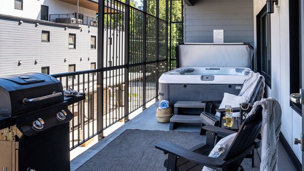 A balcony with a grill, a hot tub, and lounge chairs. - Birdies and Bears by Revelstoke Vacation (Revelstoke)