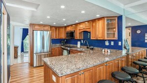 A modern kitchen with wooden cabinets, stainless steel appliances, and a granite countertop.