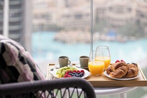 A breakfast tray with croissants, fruit, coffee, and orange juice on a table with a view of a body of water. - Sky High Burj Khalifa View - Dubai Mall (Dubai)