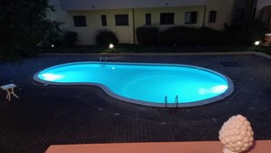 Ein schwimmender Pool in hellblau, umgeben von einem dunklen, strukturierten Deck.