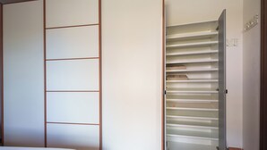 Ein Zimmer mit einer Schiebetür, die zu einem Kleiderschrank mit vielen Regalböden führt.