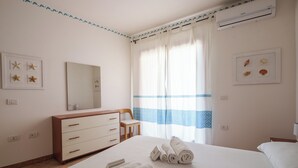 Ein Hotelzimmer mit Bett, Schminktisch, Stuhl, Spiegel und einem Fenster mit Vorhängen.
