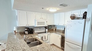 A kitchen with white cabinets, a granite countertop, stainless steel appliances, and a built-in oven.