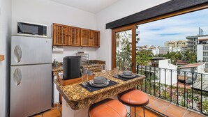 Una cocina compacta con microondas integrado, armarios de madera y un amplio ventanal con vistas a la ciudad.