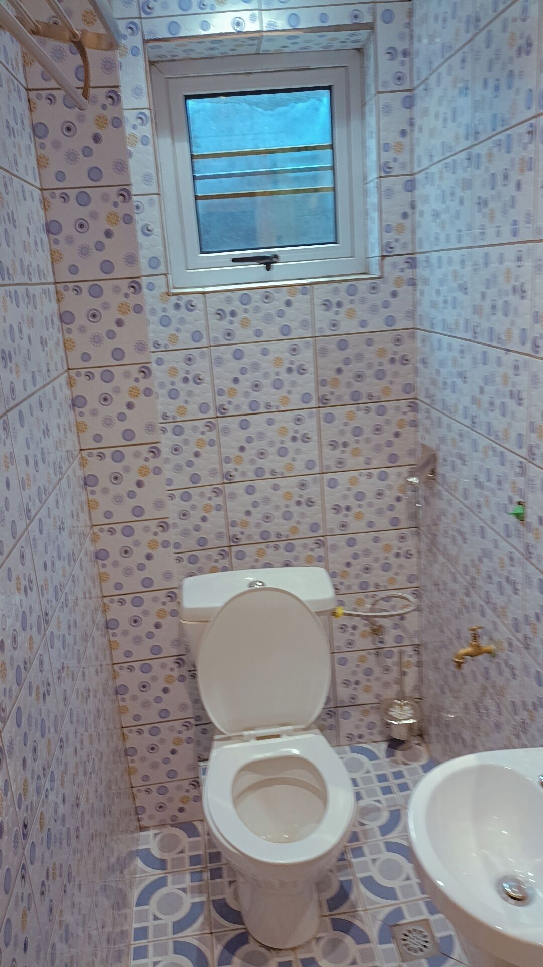 Een compacte badkamer met toilet, raam en wastafel.