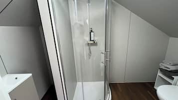 A modern bathroom with a glass shower enclosure, a white toilet, and a wooden floor.