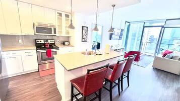 A modern kitchen with a central island, stainless steel appliances, and red bar stools.