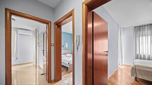 A hotel room with a wooden floor, a bed, a bedside table, and a window with curtains. - Seafront Apt, Tastefully Furnished - Neda Smilje (Kampor)