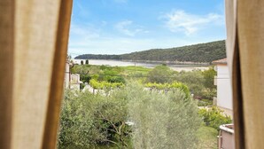 A view from a window overlooking a river, greenery, and a distant hill. - Seafront Apt, Tastefully Furnished - Neda Smilje (Kampor)